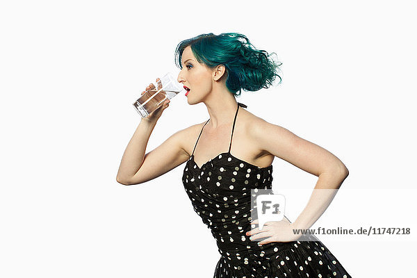 Junge Frau mit grünen Haaren trinkt Wasser vor weissem Hintergrund