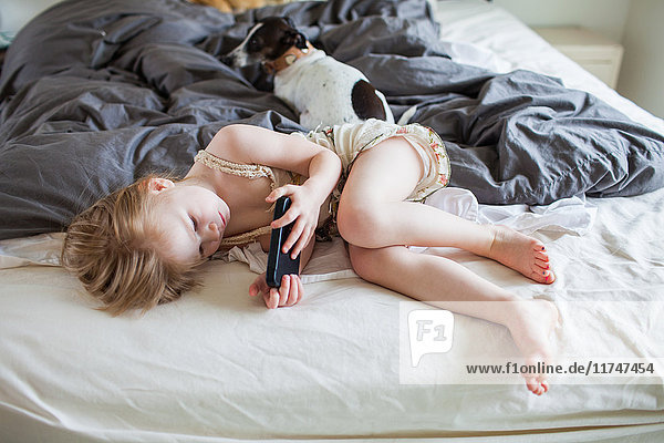 Auf dem Bett liegendes Mädchen mit Smartphone