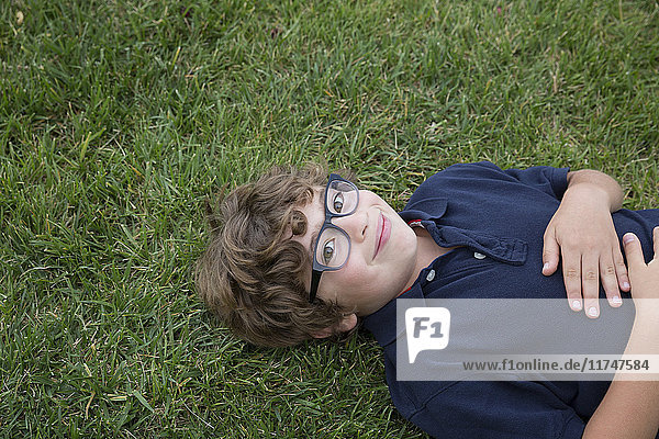 Portrait of young boy lying on back on grass