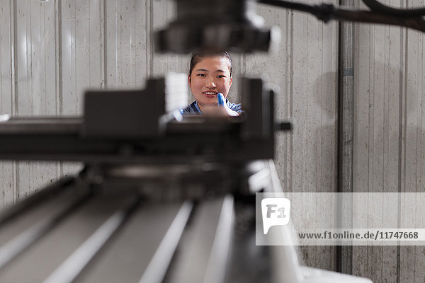 Hauptporträt einer Fabrikarbeiterin an einer Maschine in einer Kranfabrik  China