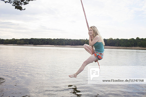 Junge Frau schwingt Seil über dem See
