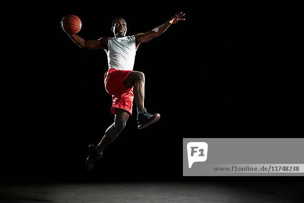 Junger männlicher Basketballspieler springt mit dem Ball