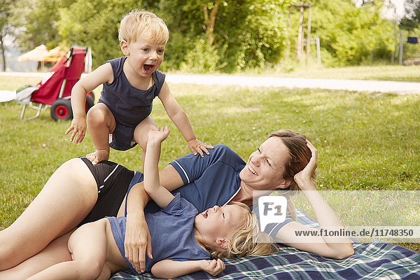 Mother and sons relaxing in park  lying on picnic blanket