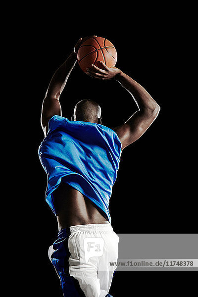 Männlicher Basketballspieler springt mit dem Ball