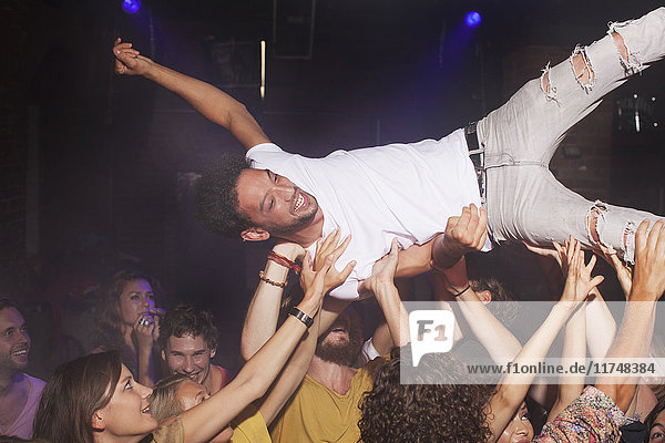 Group of people lifting man in club