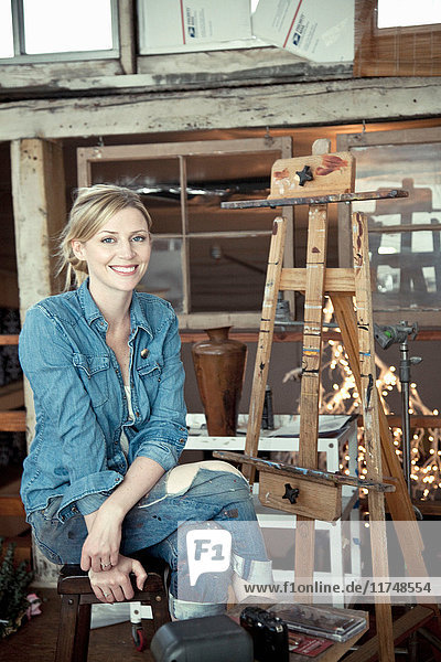 Mittlere erwachsene Frau im Atelier des Künstlers sitzend  Porträt