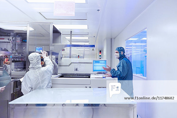 Arbeiter mit Fertigungsmaschinen in einem Reinraum einer flexiblen Elektronikfabrik