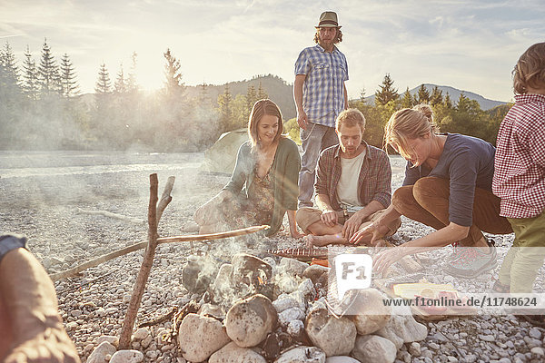 Family sitting around campfire preparing food