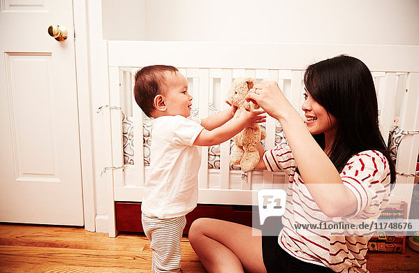 Mother playing with baby boy with soft toy