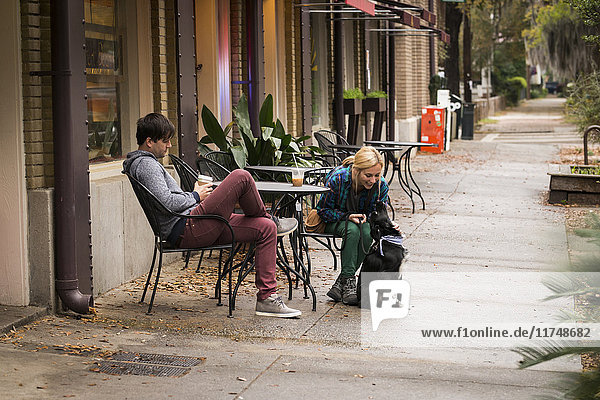 Couple with dog having coffee at sidewalk cafe  Savannah  Georgia  USA