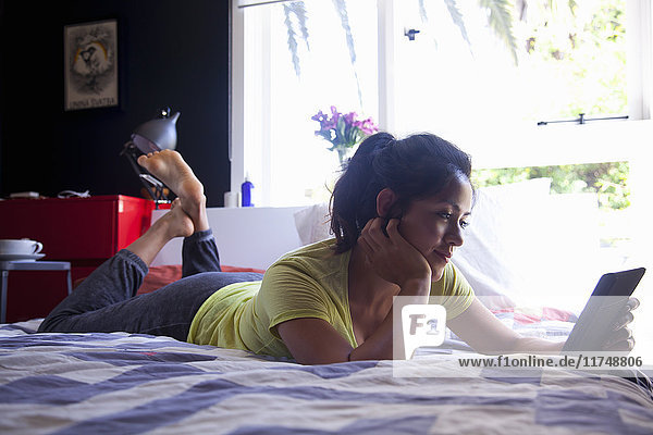 Young woman using digital tablet on bed
