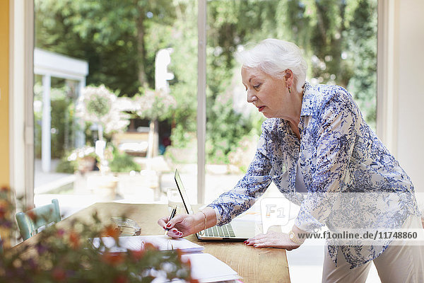 Ältere Frau schreibt im Notizbuch