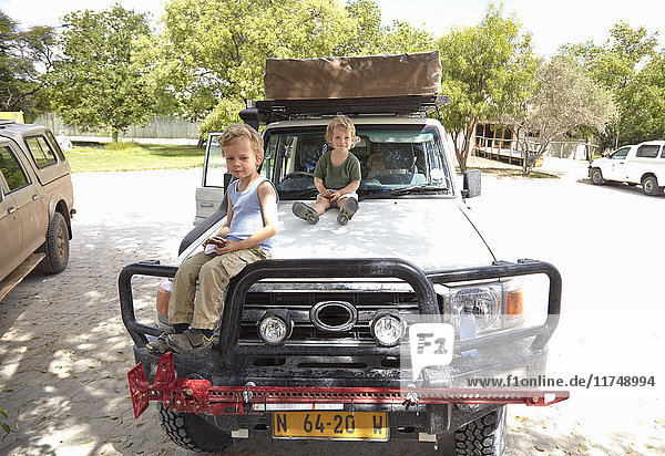 Portrait of two young boys sitting on off road vehicle  Otavi  Etosha  Namibia