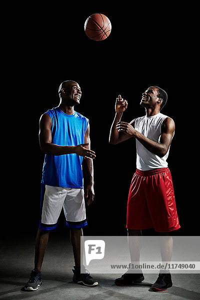 Studioaufnahme von zwei Basketballspielern mit Ball in der Luft