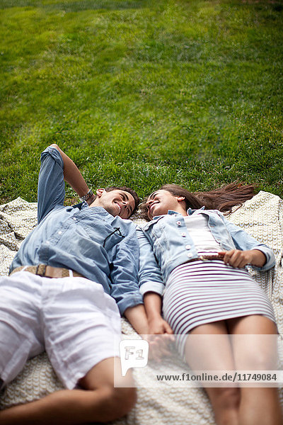 Young couple lying in park and holding hands