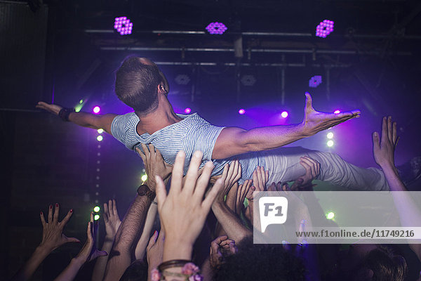 Group of people lifting man in club