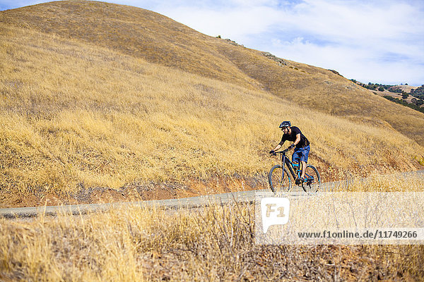 Young male mountain biker on rural road  Mount Diablo  Bay Area  California  USA