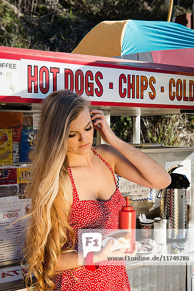 Junge Frau hält Essen am Hotdog-Stand