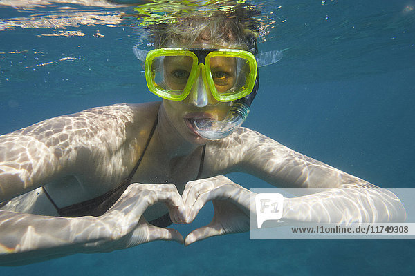 Portrait of female snorkeler making heart shape with hands  Bali  Indonesia