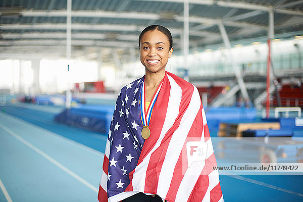 Young female athlete wrapped in US flag with gold medal