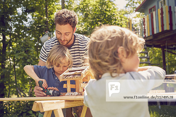 Father and two sons doing woodwork together  outdoors