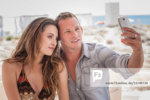 Young couple taking selfie on smartphone at beach  Castiadas  Sardinia  Italy