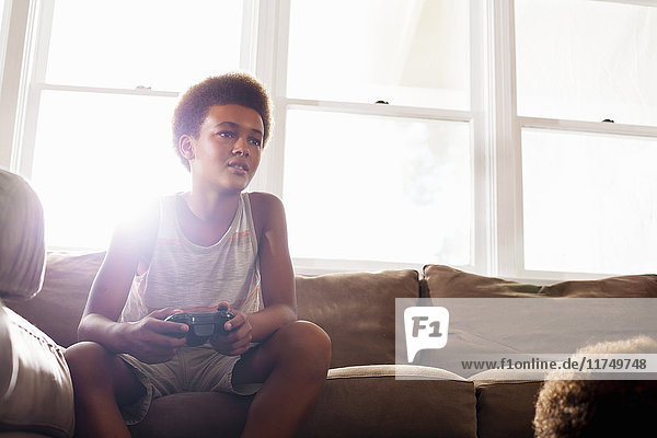 Boy using game controller from living room sofa