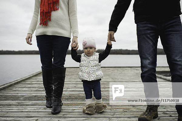 Young family  holding hands  walking on jetty  low section