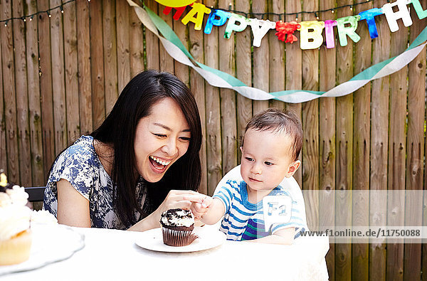 Mother and baby boy smiling with birthday cake