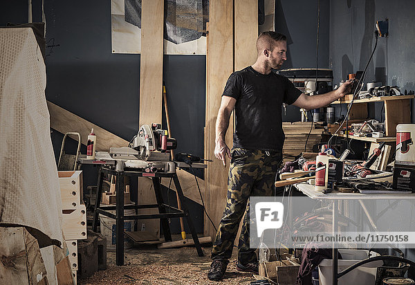 Male carpenter searching shelves in workshop