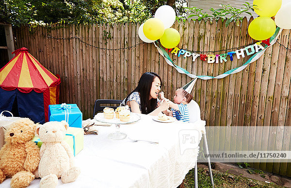 Mother and son sitting at table eating birthday cake