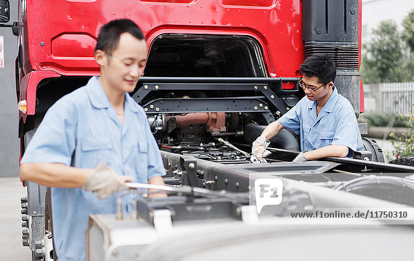 Zwei männliche Fabrikarbeiter arbeiten auf einem Lastwagen in einer Kranfabrik  China