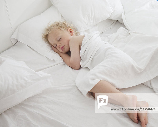 Young boy asleep on bed  under cover