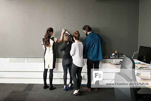 Colleagues by wall making heart shape