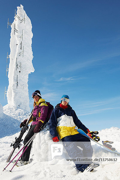 Snowboarder und Skifahrer auf dem Gipfel des Berges mit Ausrüstung  vor einer Eisskulptur