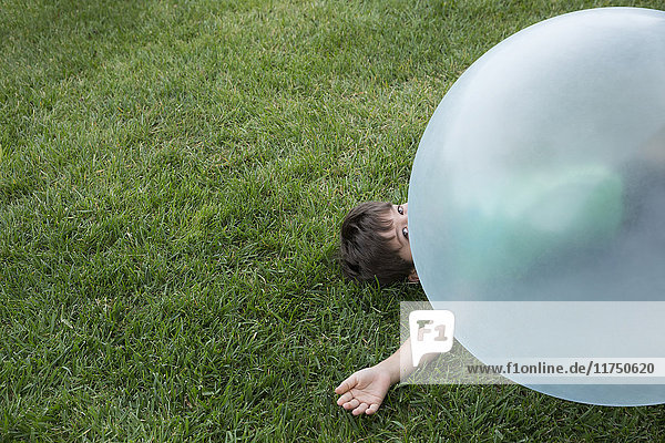 Junge liegt unter großem aufblasbaren Ball