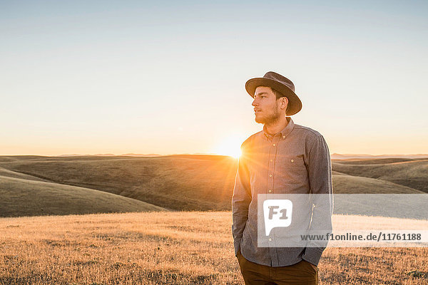 Man looking at rolling prairie hills at sunset Bakersfield California USA