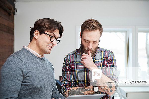 Male designers looking at digital tablet in design studio