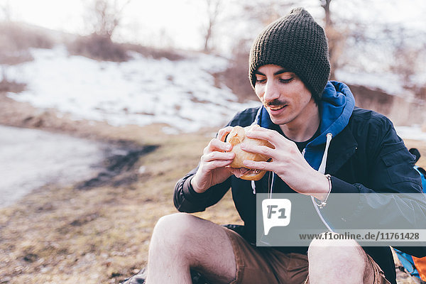 Young male hiker on roadside eating sandwich  Monte San Primo  Italy