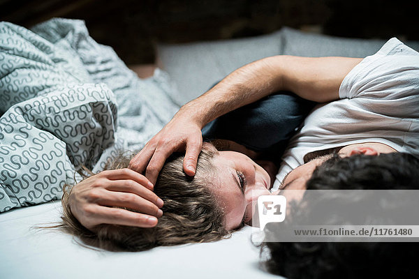 Junges Paar liegt im Bett und umarmt sich von Angesicht zu Angesicht