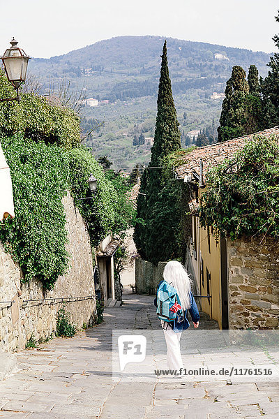 Rückansicht einer reifen Frau mit langen grauen Haaren auf gepflasterter Straße  Fiesole  Toskana  Italien