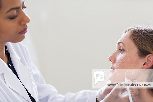Kosmetischer Chirurg  der das Gesicht des Patienten für die Operation markiert