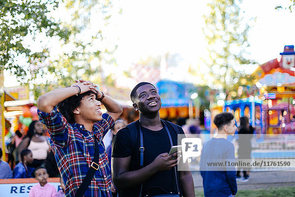 Two friends at funfair  looking up  laughing