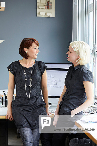 Zwei Designerinnen unterhalten sich am Bürotisch