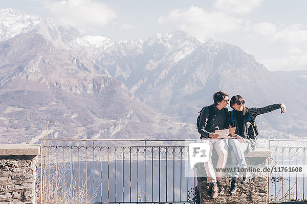 Ehepaar sitzt auf einer Terrassenmauer über dem Bergseeufer  Monte San Primo  Italien