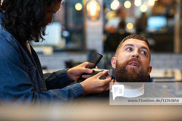 Friseur im Friseursalon schneidet Kunden den Bart