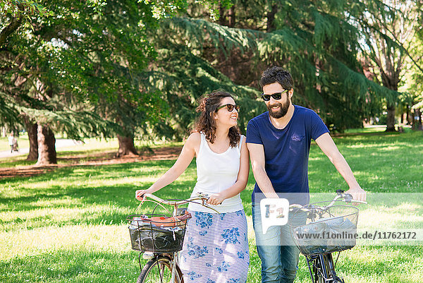 Couple strolling with bicycles in park  Arezzo  Tuscany  Italy