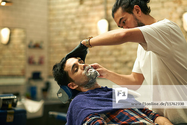 Hairdresser in barbershop giving customer wet shave