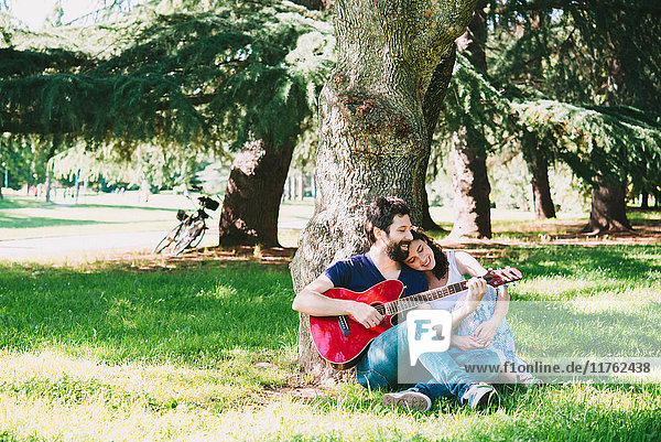 Paar sitzt im Park und spielt Gitarre  Arezzo  Toskana  Italien