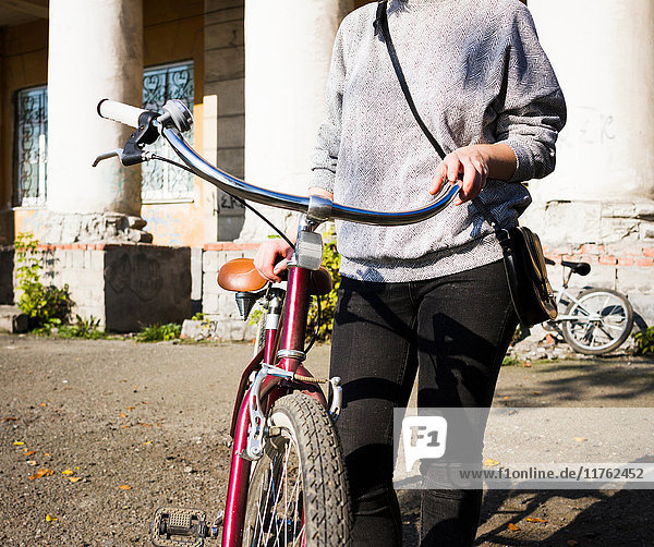 Nackenansicht einer jungen Frau mit Fahrrad im Stadtgebiet
